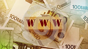 WWW - wooden blocks with letters, laying on 100 euro banknotes. Top view. World wide web Internet business concept