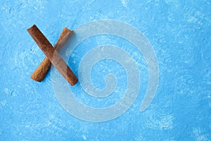 X from cinnamon sticks, innamon sticks on wood table with bundles of cinnamon in soft focus in background.