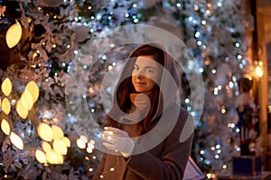 X-mas street celebration. woman walking and shopping before Christmas. street girl portrait near decorated night showcase of shops