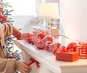 x-mas, winter holidays and people concept - happy young woman decorating christmas tree with ball at home