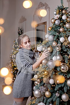 X-mas, winter holidays and people concept - happy young woman decorating christmas tree at home