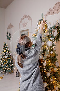 X-mas, winter holidays and people concept - happy young woman decorating christmas tree at home