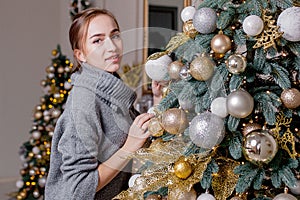 X-mas, winter holidays and people concept - happy young woman decorating christmas tree at home