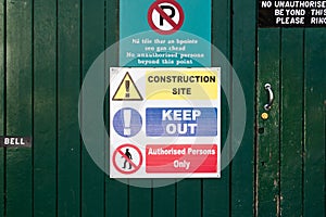 A "Construction Site, Keep Out and Authorised Persons only" phrase on a sign  on a green wooden wall