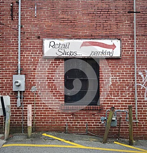 "Retail Shops...parking" Hand-Painted Directional Arrow Sign on Brick Wall Background.