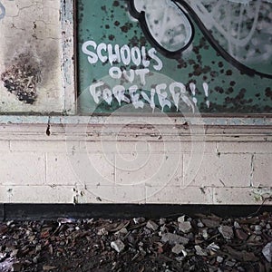 & x22;School& x27;s Out Forever!!& x22; Graffiti on Classroom Blackboard in an Abandoned School Building.