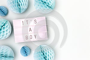 It's a boy. Lightbox with letters and tissue paper balls in a blue color.