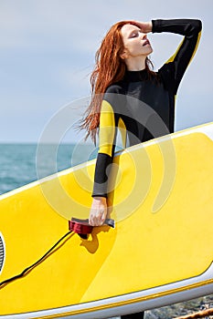 It's time for surfing. Pretty young caucasian woman holding surf board on sea shore