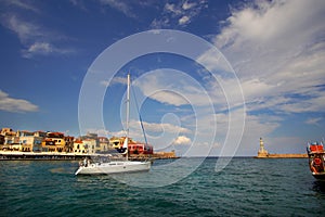 Xania, Crete, October 01 2018 Panoramic view of the Venetian harbor with its ancient lighthouse and a sailing vessel photo