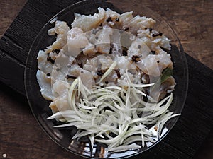 XE salad of freshly salted river pike fish on a cutting kitchen board with ingredients for cooking. Pike fillet pieces. Wooden