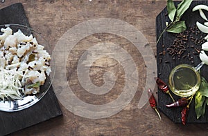 XE salad of freshly salted river pike fish on a cutting kitchen board with ingredients for cooking. Pike fillet pieces. Wooden