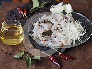 XE salad of freshly salted river pike fish on a cutting kitchen board with ingredients for cooking. Pike fillet pieces. Wooden