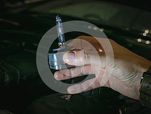 A xenon light bulb in the man's hand. A professional worker changes the new xenon lamps of the car