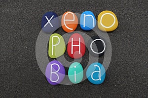 Xenophobia, social issue concept word composed with colored stones over black volcanic sand