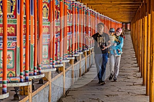 XIAHE, CHINA - AUGUST 24, 2018: People pass a row of praying wheels around Labrang Monastery in Xiahe town, Gansu