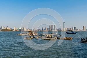 Xiamen Haicang Bay Park landscapes, Fishing Boats on the ocean and Xiamen City Skyline at distance