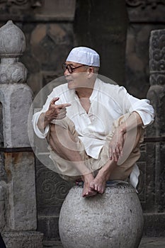 Portrait of a man wearing a taqiyah sitting at a stone, at the Xian Great Mosque in the city of Xian in China