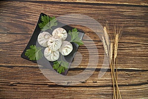Xiaolongbao Chinese steamed bun on black plate, wheat ears, top view, old wood background