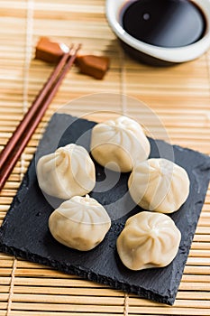 Xiaolongbao, traditional steamed dumplings and soy sauce. Xiao Long Bao buns on cutting board