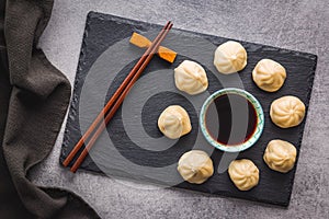 Xiaolongbao, traditional steamed dumplings and soy sauce. Xiao Long Bao buns on cutting board. Top view