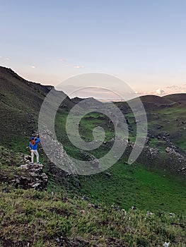 Xilinhot - A man standing on a green hill in Xilinhot, Inner Mongolia and enjoys a sunset. He is wearing a cowboy hat.