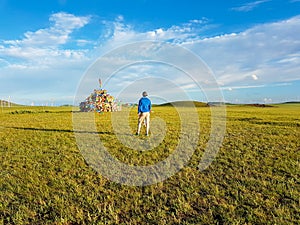 Xilinhot - A man standing on a vast pasture in Inner Mongolia, and admiring a heap of stones aobao with colorful prayer flags