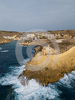 Xlendi tower on the rock and rough waves at Xlendi bay aerial Gozo Malta