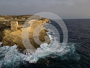 Xlendi Tower and rocky coastline with waves after storm aerial Gozo Malta