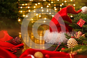 Xmas banner: santa hat with christmas decorations: cone, balls, tape, beads, gift box and Christmas tree on garland bokeh