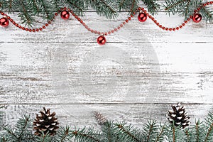 Xmas card. Old wooden Christmas background. Fir branches and cones. Red baubles and garlands. Top view