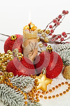 Xmas composition with red baubles, gold garland, candle and ribbon on white snow. Christmas card background