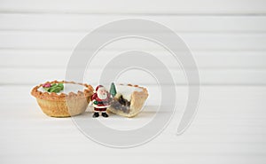 Christmas photography image of christmas food mince pies and mini santa claus on white wood background