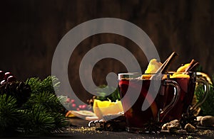 Xmas hot mulled red wine with spices and fruits on wooden rustic table. Traditional Christmas hot drink in festive table setting