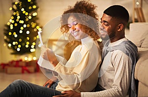 Xmas magic. Joyful black spouses opening Christmas gift together