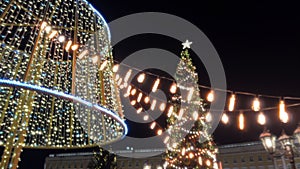 Xmas sparkles. Christmas eve. Glow of Christmas lights hanging on garland against huge Christmas tree. Low Winde angle