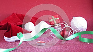 Xmas, winter, new year concept - red Christmas background covered with white snow Santa hat with burning candle and toy