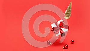 Xmas wreath. Golden winter tree, white gift box with red ribbon fall with balls in Christmas composition on dark red background