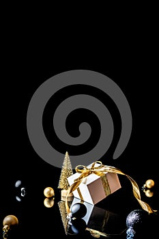 Xmas wreath. White gift with golden bow, gold balls and new year tree in Christmas decoration on dark background for greeting card