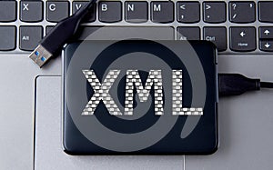 XML - acronum on an external drive in gray letters on the background of a laptop