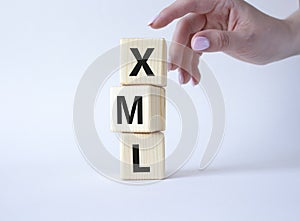 XML - Extensible Markup Language. Wooden cubes with word XML. Businessman hand. Beautiful white background. Business and photo