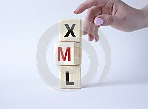 XML - Extensible Markup Language. Wooden cubes with word XML. Businessman hand. Beautiful white background. Business and photo