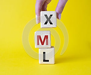 XML - Extensible Markup Language. Wooden cubes with word XML. Businessman hand. Beautiful yellow background. Business and photo