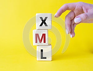 XML - Extensible Markup Language. Wooden cubes with word XML. Businessman hand. Beautiful yellow background. Business and photo