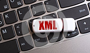 XML - the word on a white flash drive, lying on a black laptop keyboard