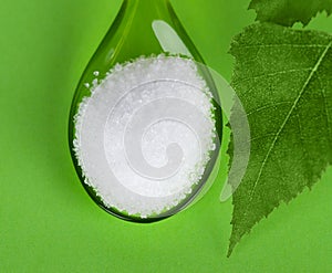 Xylitol birch sugar on green plastic spoon