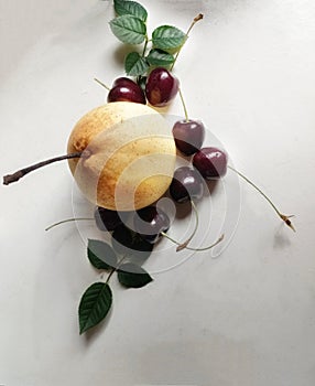 Ya pear surrounding by cherries on the white table