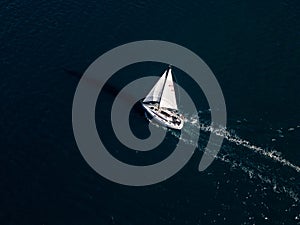 A yacht with all sails set races across the sea, propelled by the wind. Aerial view