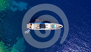 Yacht anchoring in crystal clear turquoise water in front of the tropical island, alternative lifestyle, living on a boat. Aerial