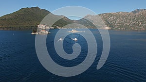The yacht and the boat sail towards each other near the islands in the Bay of Kotor