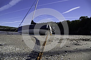 Yacht boat on a sandy beach tethered with a rusty chain